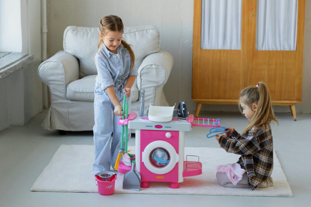 Two young girls play with a toy cleaning set in a cozy living room setting.